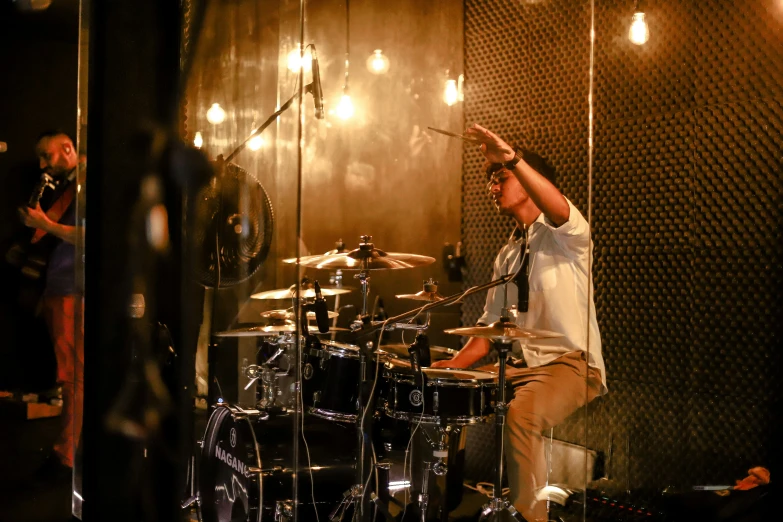 a drummer in a recording studio holds his hands up