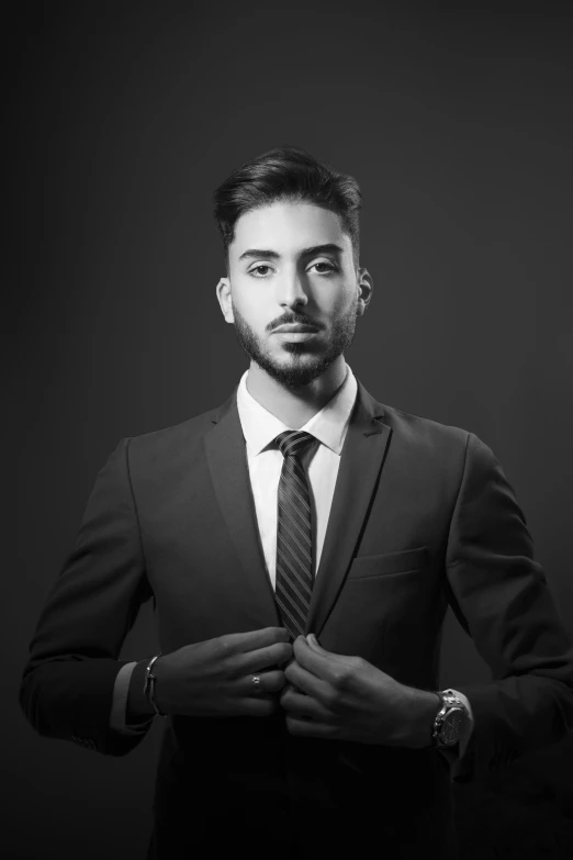 the man is looking into his phone while he is tying his tie