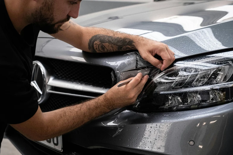 a man in black shirt painting a car with white and black lettering