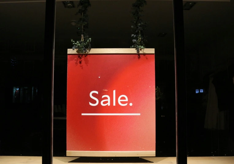 a big sale sign is displayed inside a shop window