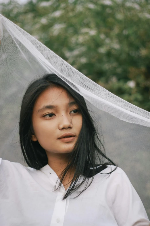 an asian woman wears a long white veil on her head