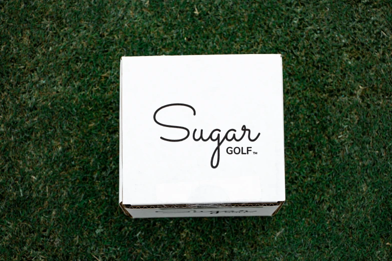 a box of sugar golf sitting on top of a lush green field