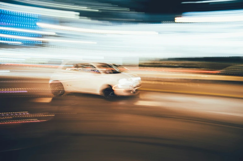 white car going down the road at night