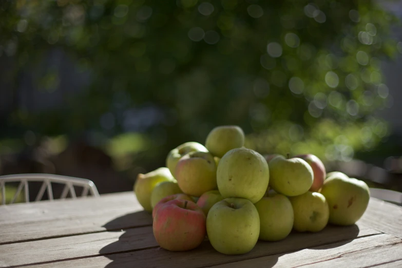 a bunch of green apples are stacked up on a table