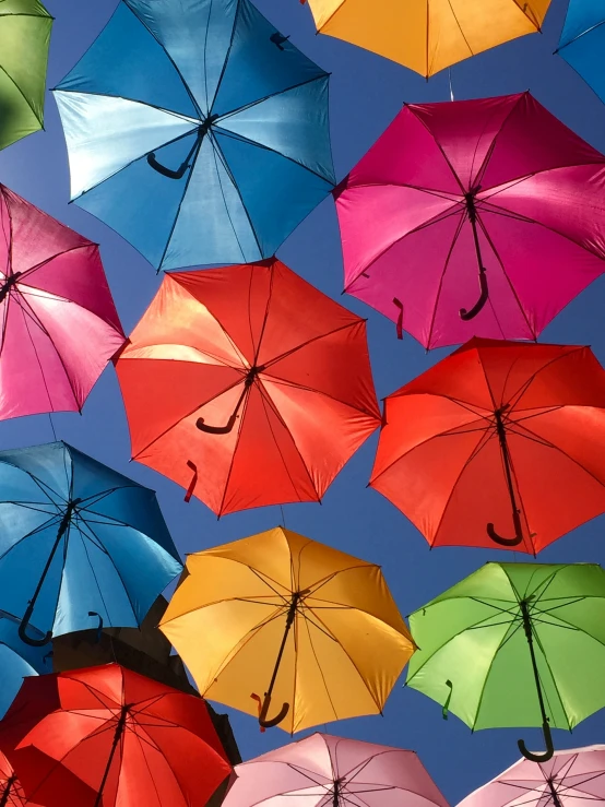 a group of umbrellas in various colors are flying through the air