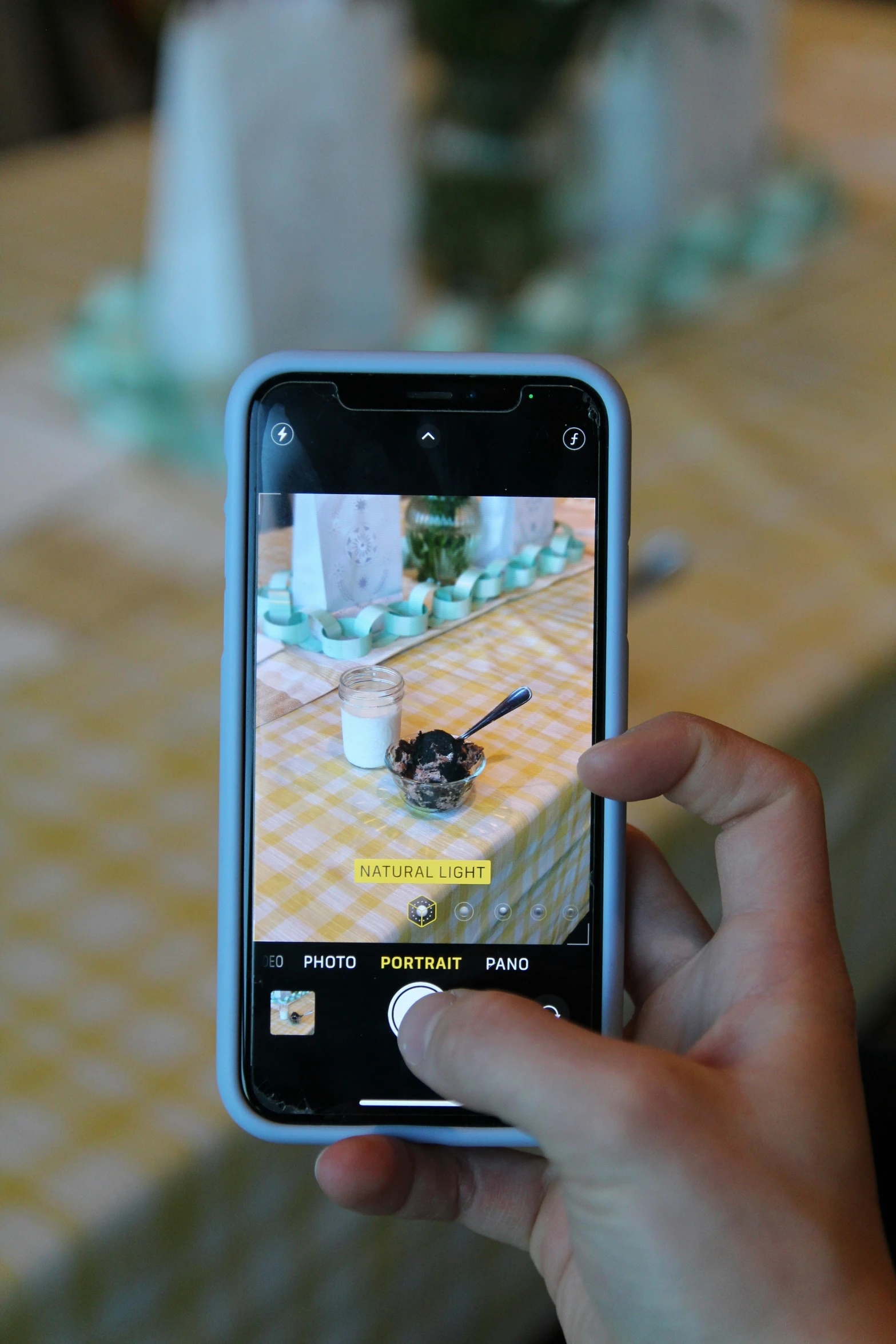 a person taking a picture of a table with flowers