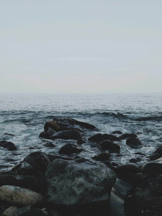 the beach has lots of large rocks near the ocean