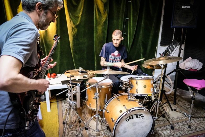 some men are playing music in front of green curtains