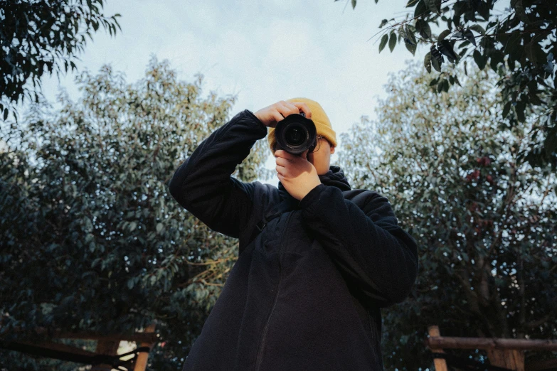 person taking a picture in front of trees with their camera