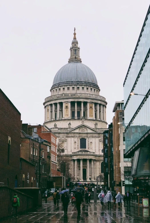 people are walking on a rainy day by a building