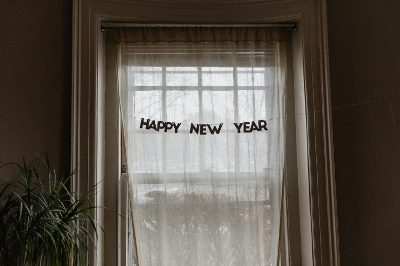 there is a happy new year sign hanging from the window