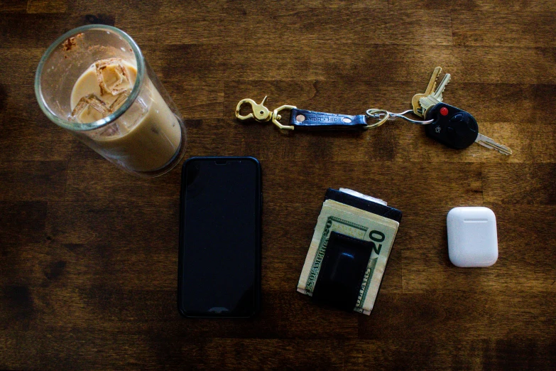 an iced drink is next to a phone, credit card, keys, and wallet