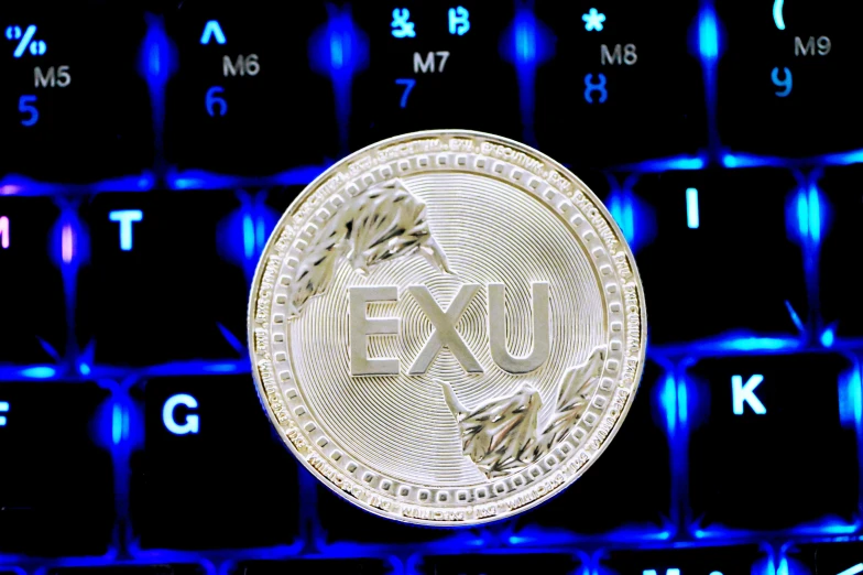 a bit coin sitting on a keyboard that is illuminated with blue light