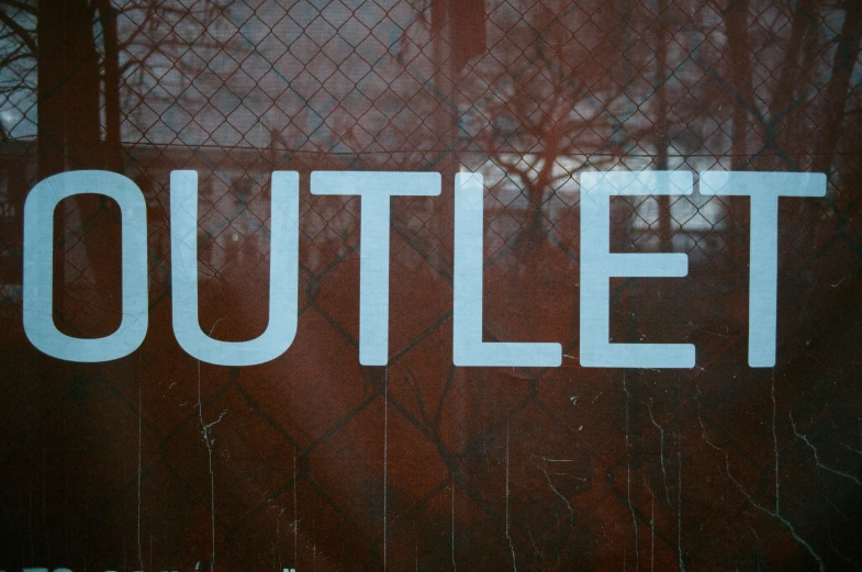 an out door sign in front of a wire fence
