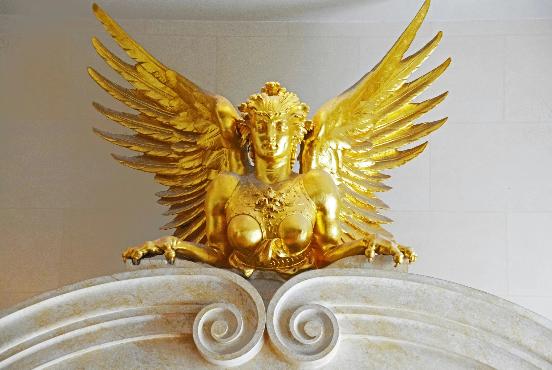 a large gold eagle statue in front of a wall