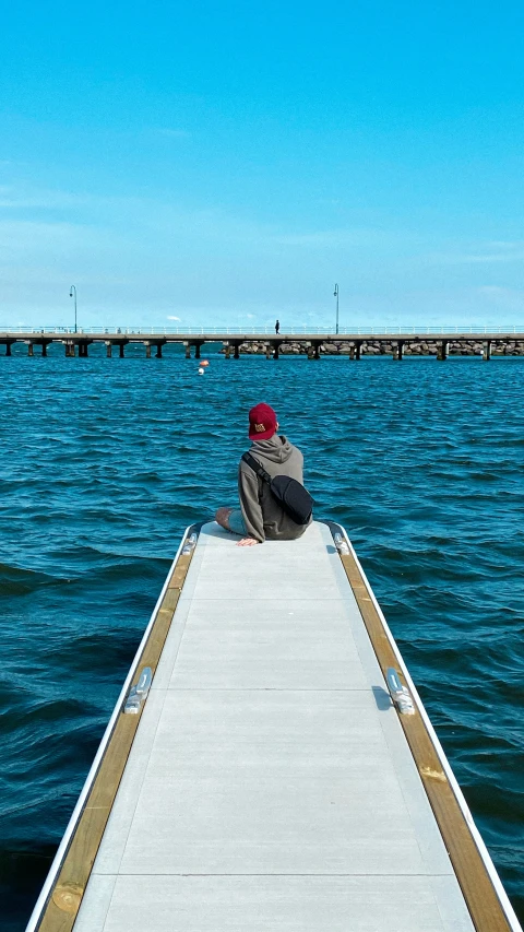 a person sitting on the end of a pier