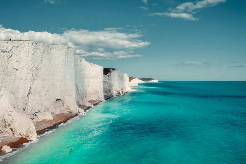 this view shows clear water near the rock wall, with a white cliff separating it from the blue water