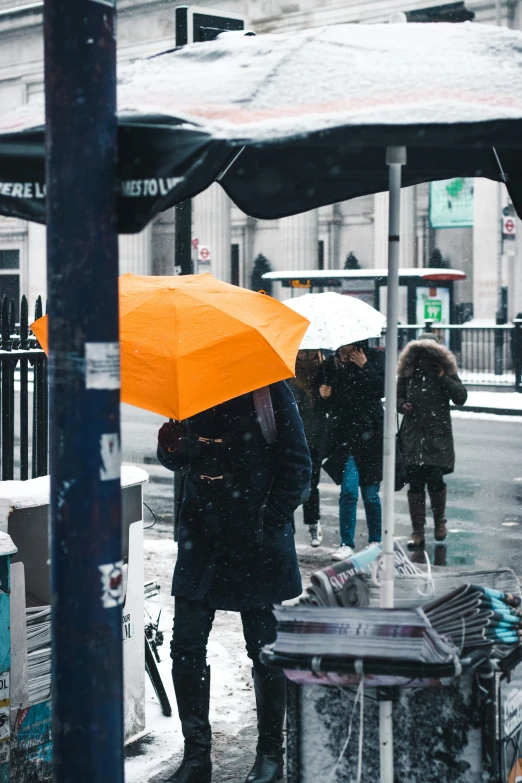 people on the street during winter with an orange umbrella