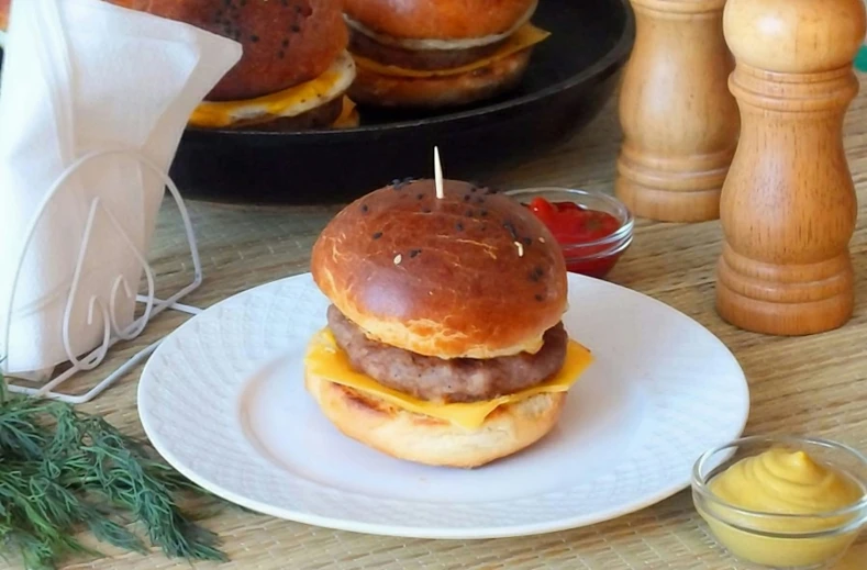 a hamburger is on a plate near a bowl of mustard