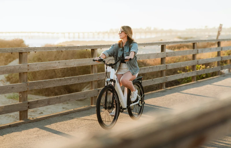 a woman riding a bike on the boardwalk