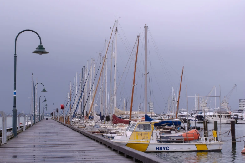 many different boats on the water near a pier