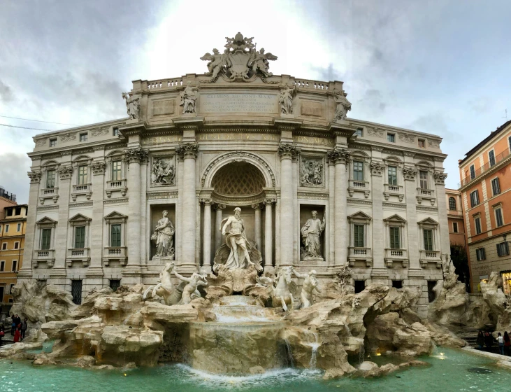 a beautiful fountain with statues and people in front