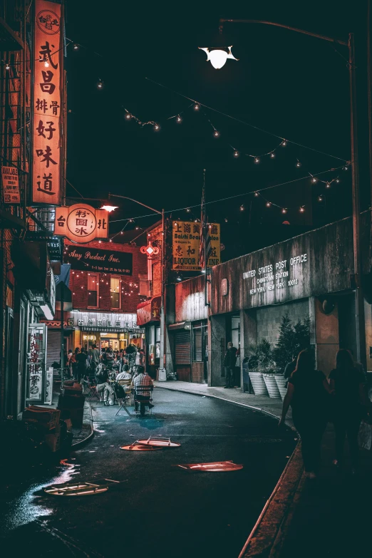 an asian city at night with some people standing on the side walk