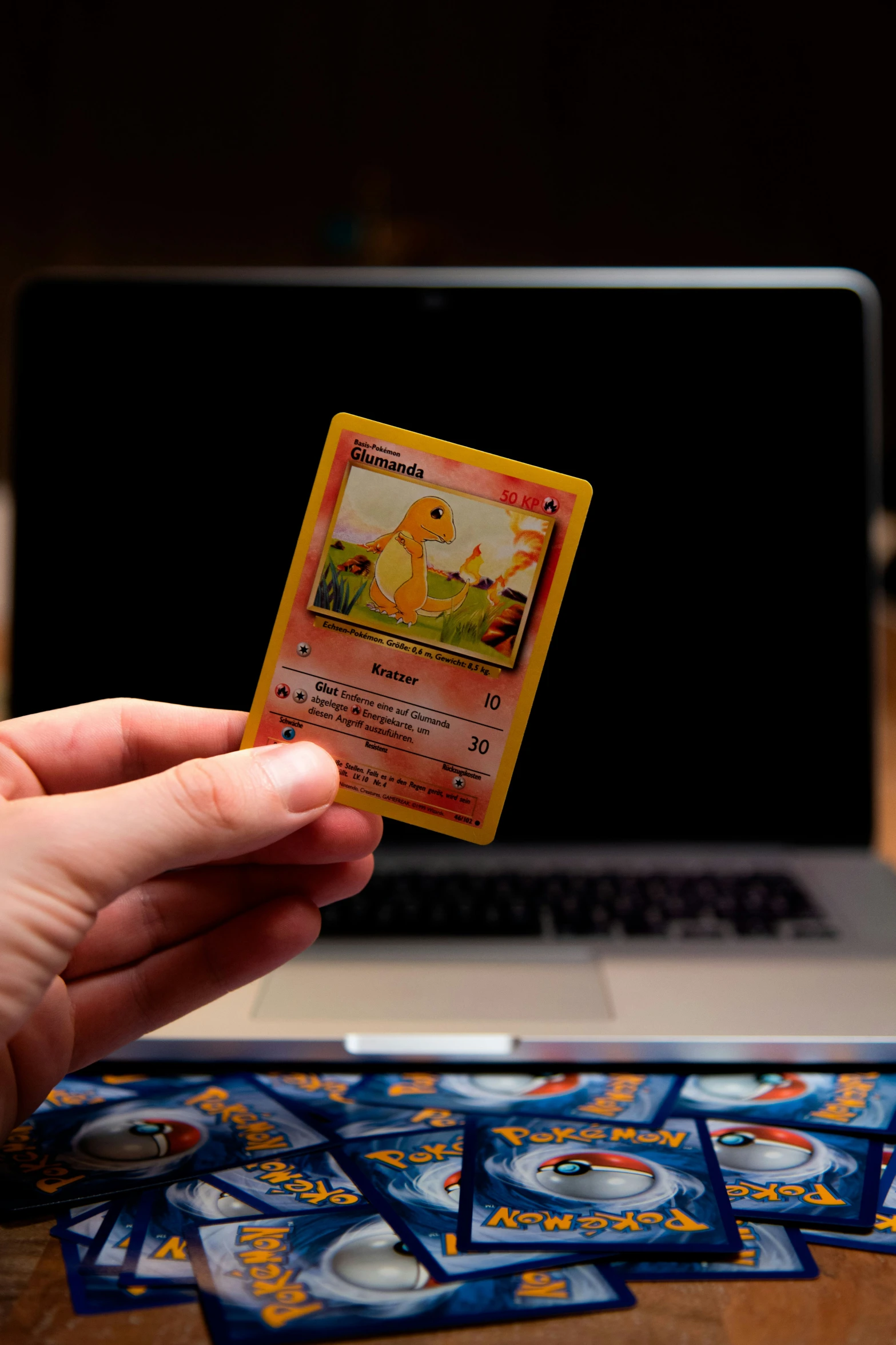 a person holding up a small plastic card in front of a laptop