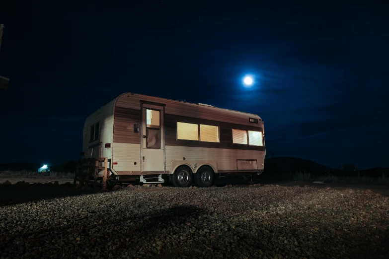 a trailer sits alone in the dark with a full moon