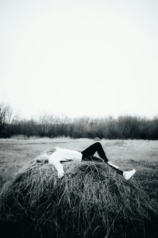 the girl is laying down on a hay bail
