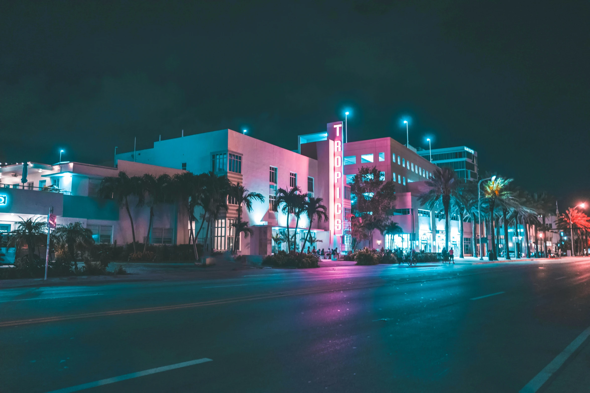 an urban street at night, with a building on the corner