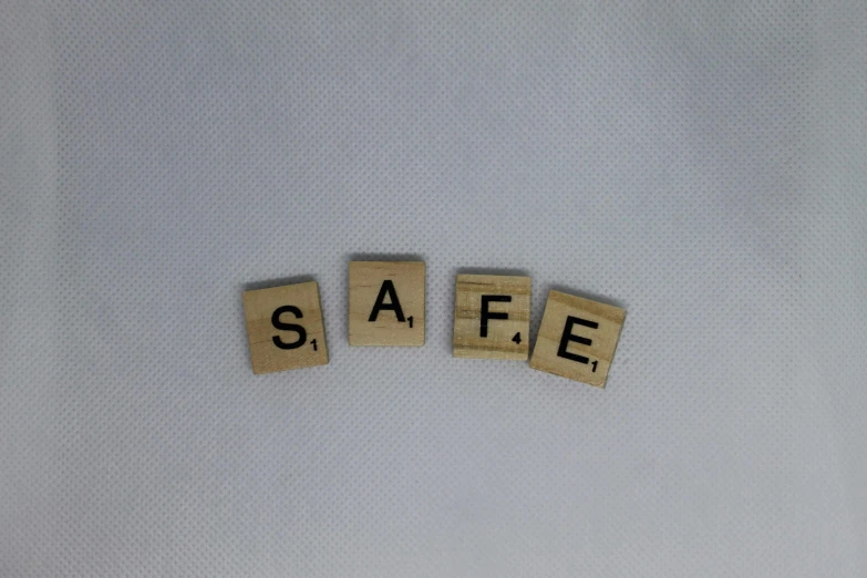 scrabbled wooden letters spelling safe are spelled by scrabble tiles