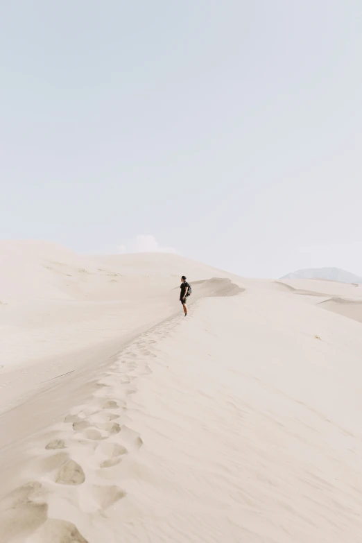 the person is hiking along the very tall white dunes