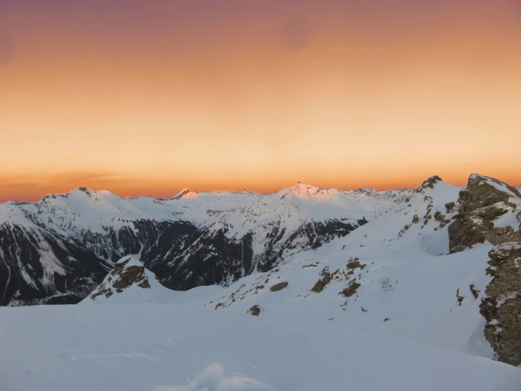 a ski boarder is holding his ski poles up as he stands on top of a snow covered mountain