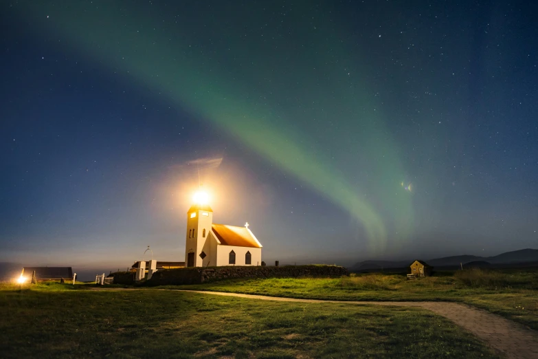 an aurora light shines in the night sky above a church