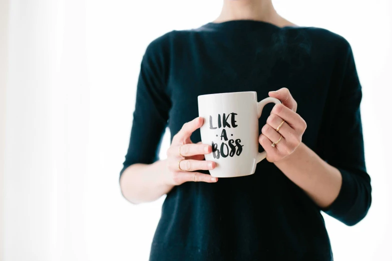 the person is holding a cup with an interesting slogan