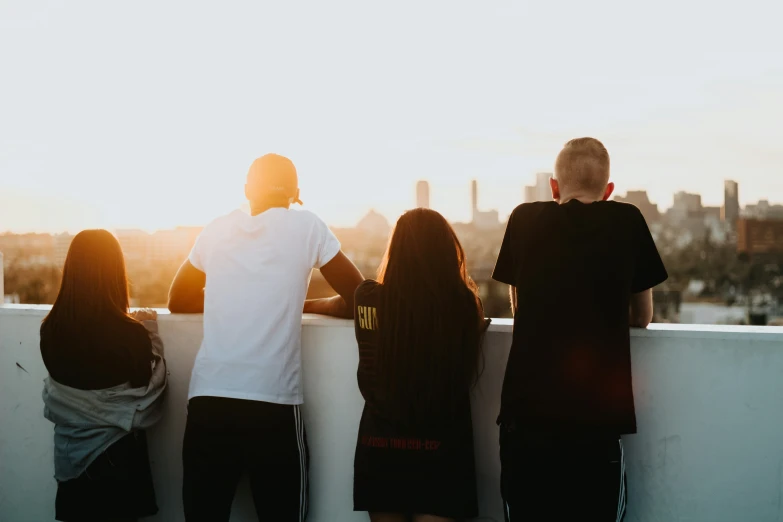 five people stand on a ledge watching the sun rise