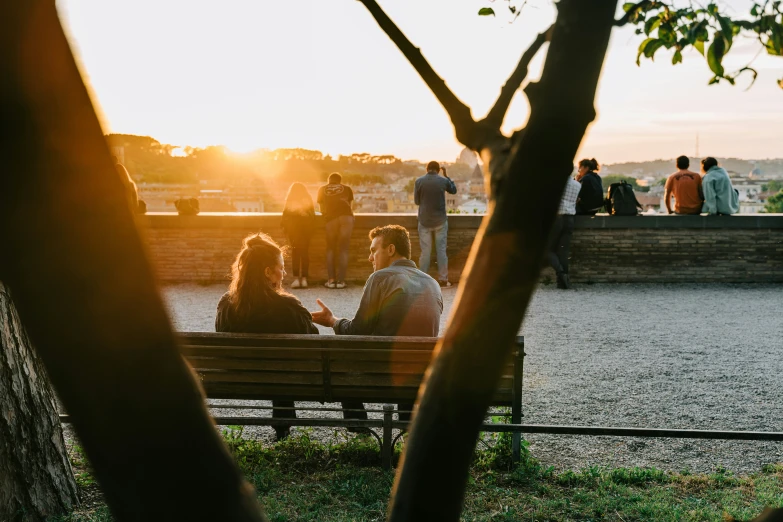 people are sitting on the bench in a park