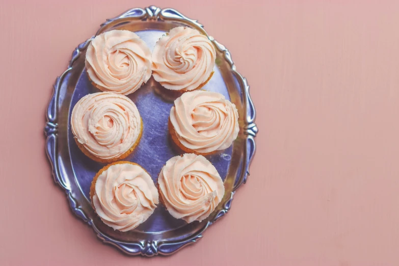 a plate filled with cupcakes with white icing