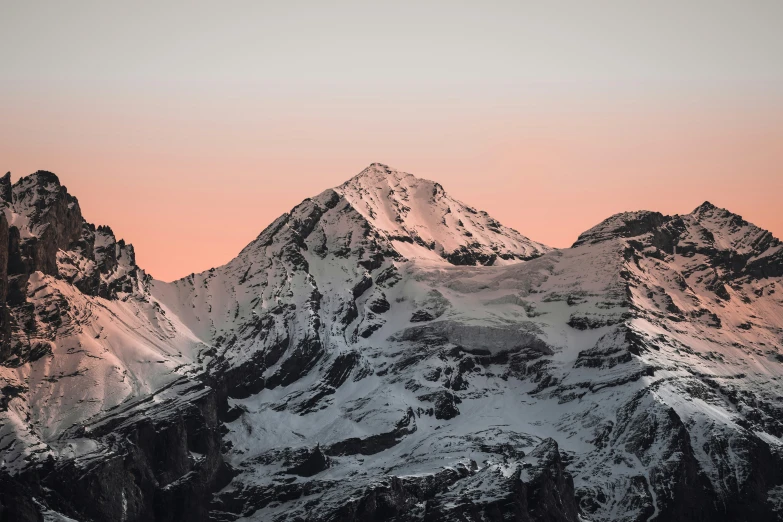 a snow covered mountain is silhouetted by the red sky
