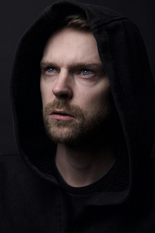 a man in a hooded jacket looks into the camera