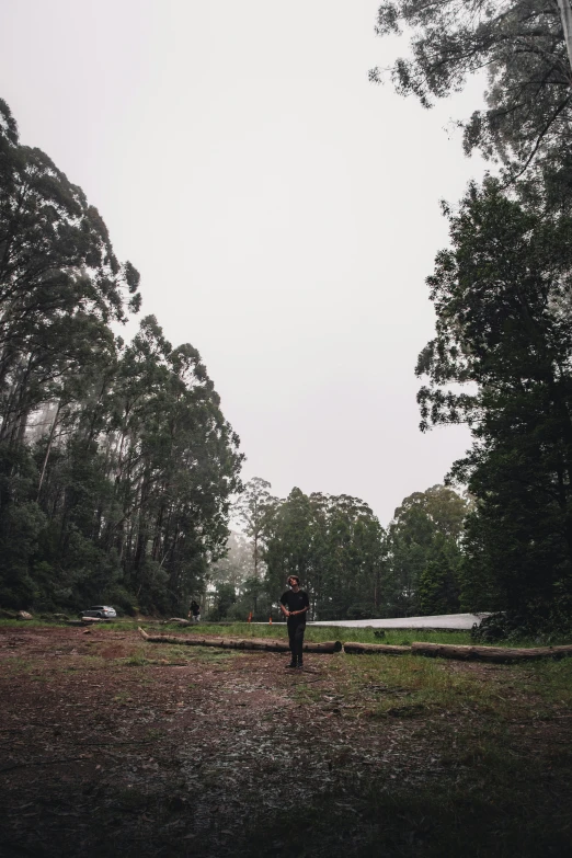 person standing in a field with trees and a boat on the horizon