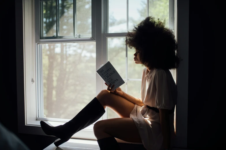 a  sitting by a window reading a book