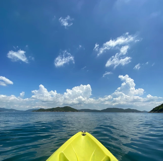 yellow kayak in open water near islands under blue sky