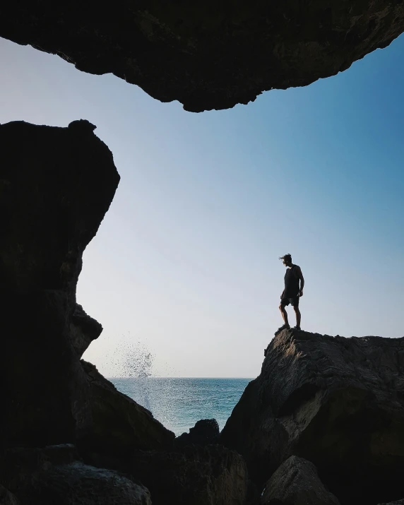 a person standing on rocks near the ocean