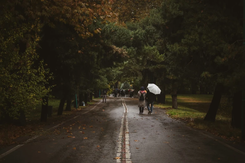 the umbrella is on the man and there is only one person standing in the road