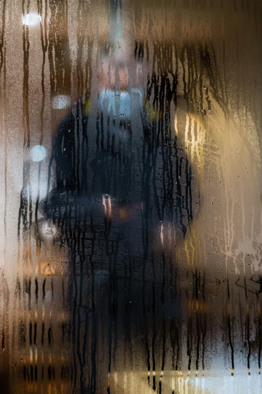 the image shows rain on the window and the reflection of buildings