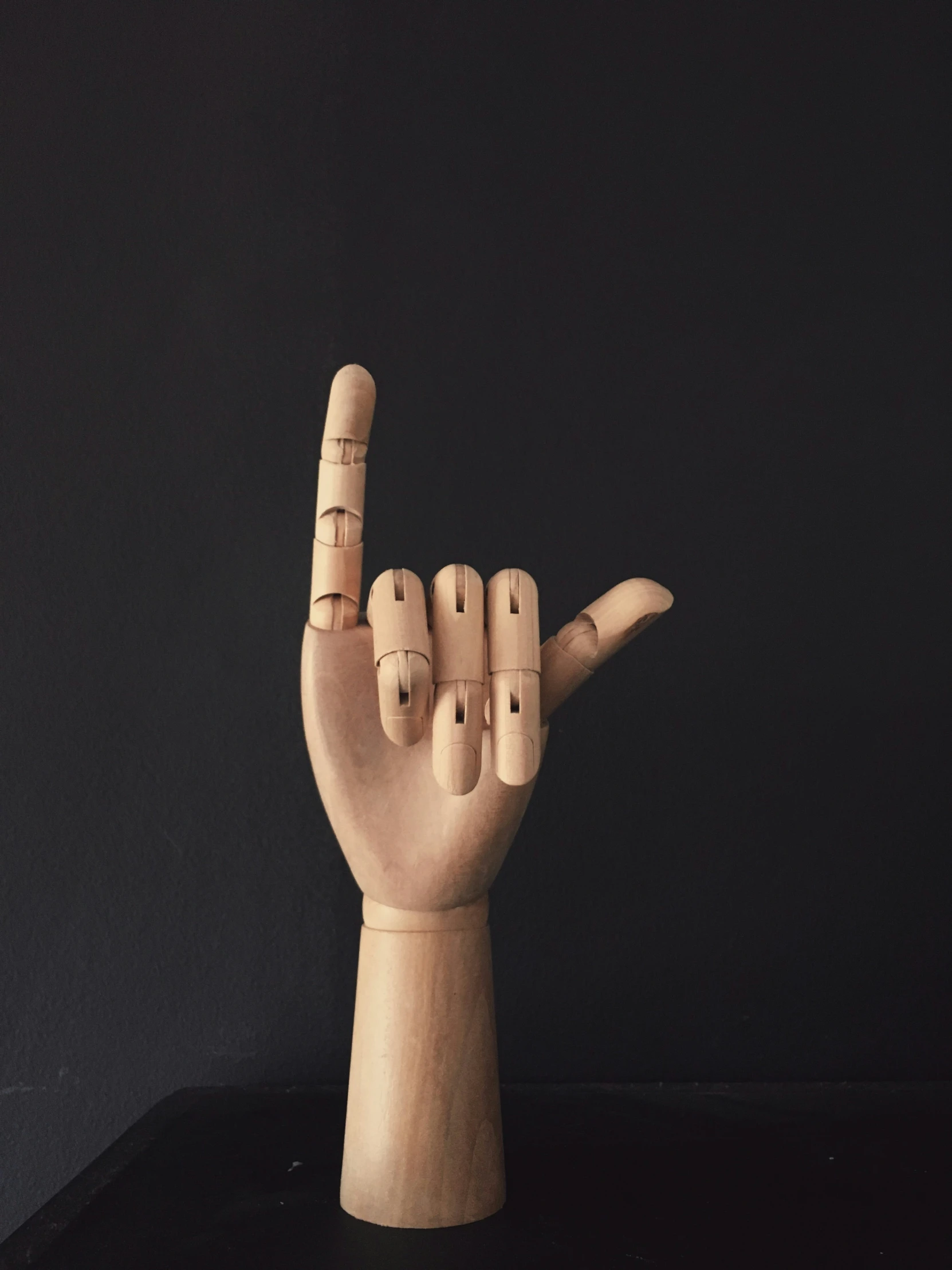 a carved wood sculpture showing the fingers in a gesture