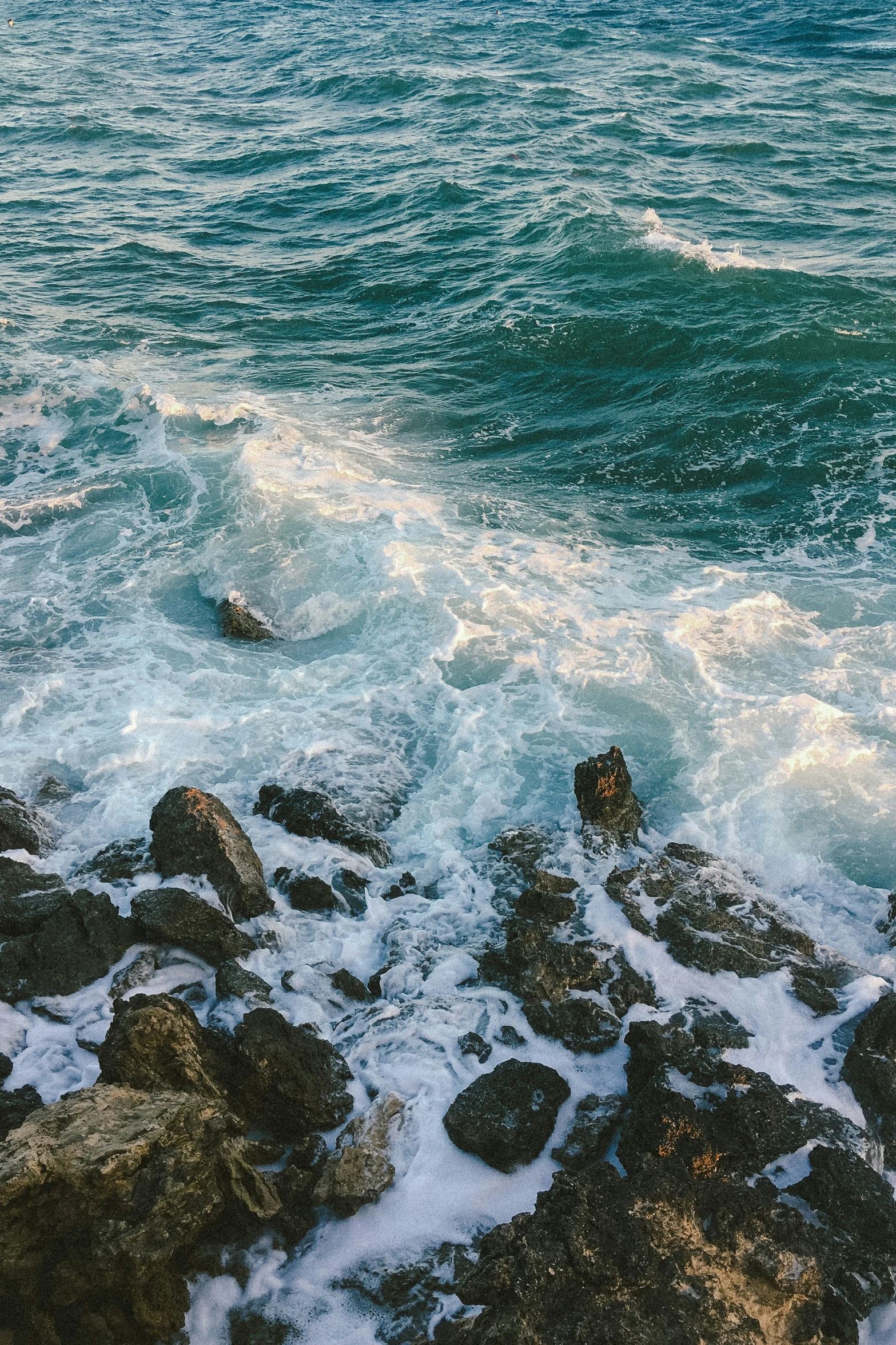 some water waves crashing over the rocks on the shore