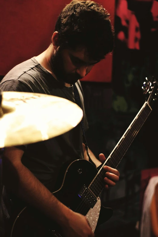 man playing guitar in dark room with large red light